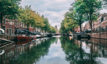 Scenic view of iconic Amsterdam canal with boats and historic buildings lining the waterway.