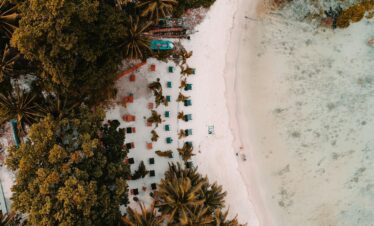 Aerial view of a tropical beach with sun loungers, palm trees, and white sand in the Andaman Islands.