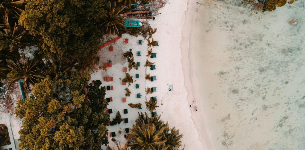 Aerial view of a tropical beach with sun loungers, palm trees, and white sand in the Andaman Islands.